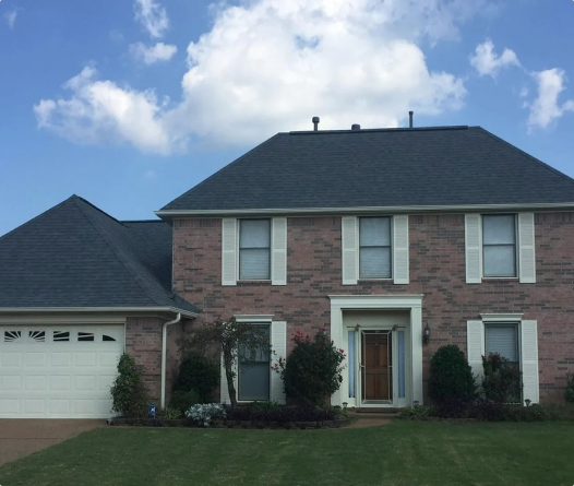 Two-story brick house with garage and green lawn.