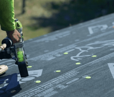 Worker using nail gun on roof underlayment