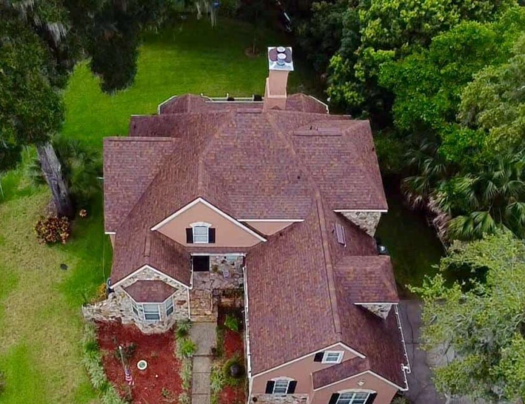 Aerial view of brown-roofed house surrounded by trees.